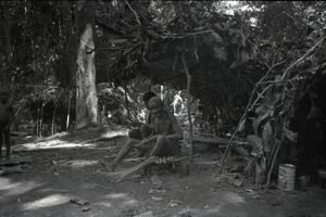 Bombé and Adamo sat underneath a shelter on a raised platform made of logs. Bombé and Adamo sat underneath a shelter on a raised platform made of logs.