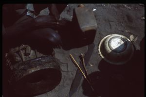 Aerial view of somebody sitting on a drum with a blade, overturned metal vessel and plastic jerrycan on the ground. Aerial view of somebody sitting on a drum with a blade, overturned metal vessel and plastic jerrycan on the ground.