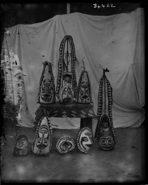 group of painted masks, arranged on and around table with bark cloth covering, against white cloth backdrop group of painted masks, arranged on and around table with bark cloth covering, against white cloth backdrop